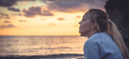 Girl looking at sunset at beach - epilepsy website