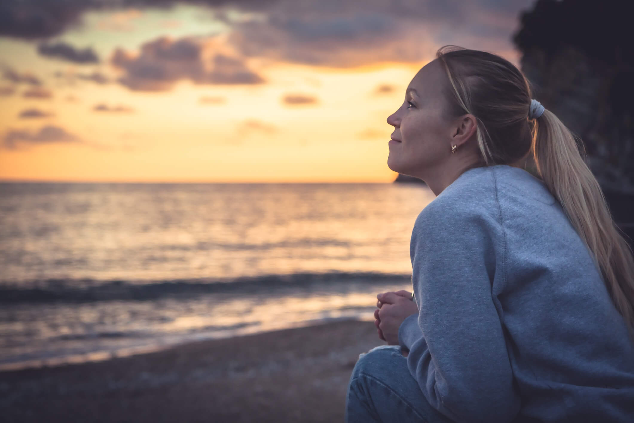 Girl looking at sunset at beach - epilepsy website